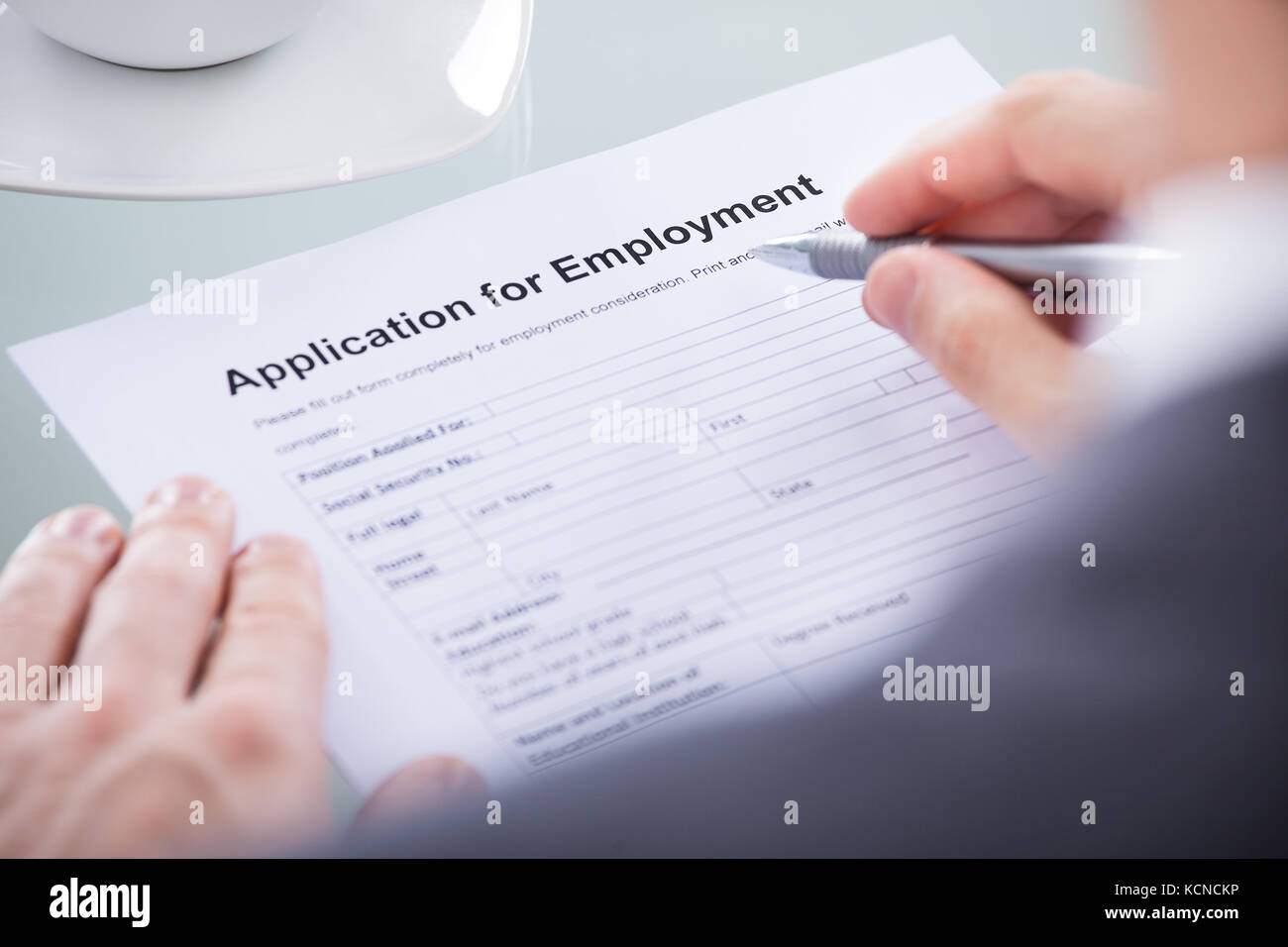 Close Up Of Businessperson Hand With A Pen Over Blank Application Form Stock Photo