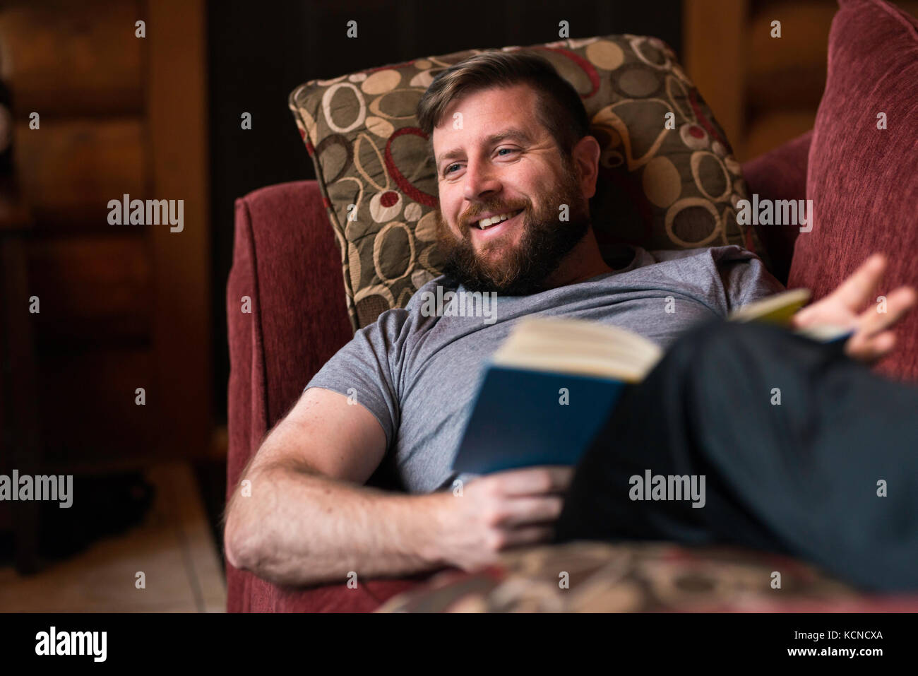 Man (40) sitting by a warm open fire at a log cabin ski chalet in Mont Tremblant, Quebec, Canada Stock Photo