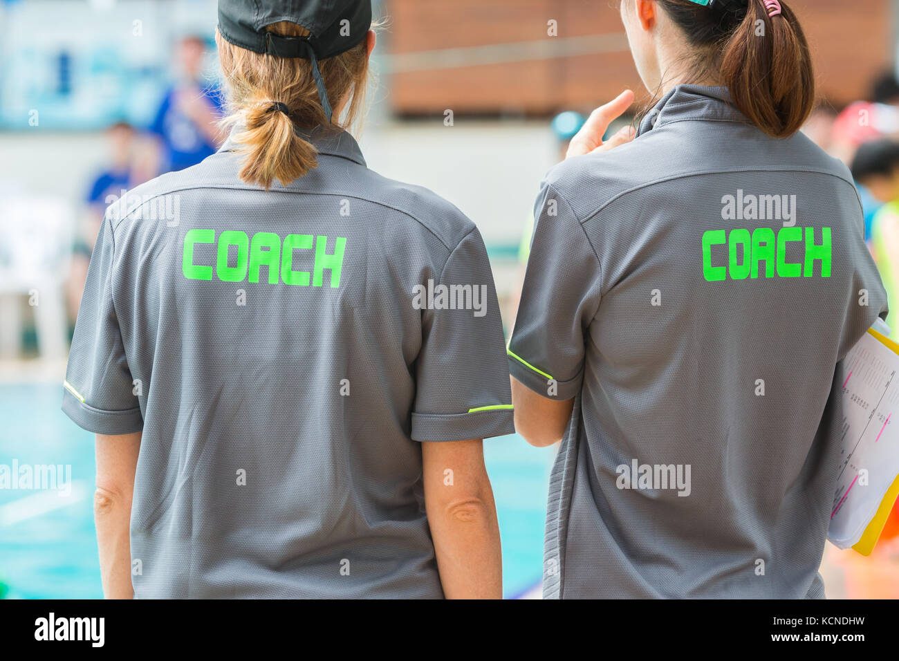 back of two coach's grey shirts with the green word Coach written on
