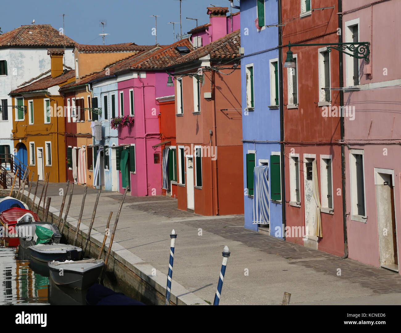 Many colorful houses in the island of Burano near Venice and boats in the canal Stock Photo