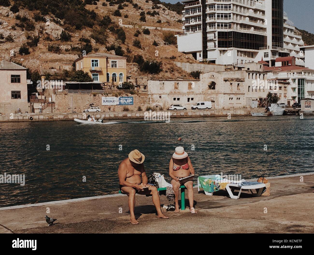 Balaklava, Crimea - September 19, 2017: elderly couple on sea shore of bay read newspapers Stock Photo
