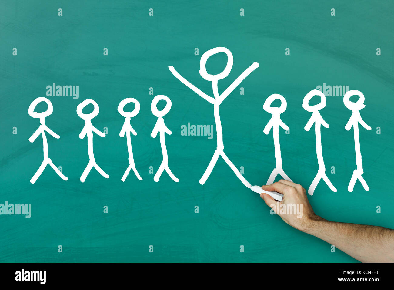 Standing out from crowd concept on green blackboard Stock Photo