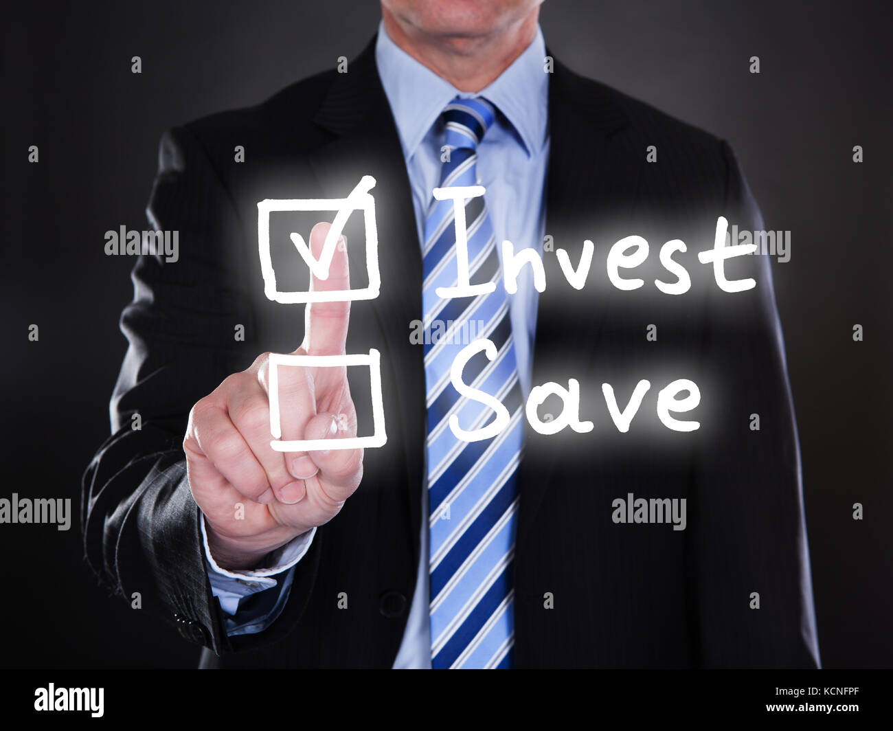 Businessman selecting invest option on the screen over black background Stock Photo