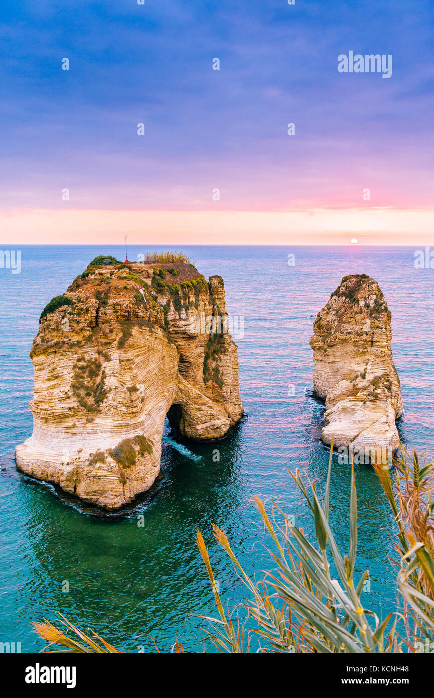 Beautiful sunset on Raouche, Pigeons' Rock. In Beirut, Lebanon.Sun and Stones are reflected in water.dense clouds in the sky. Stock Photo