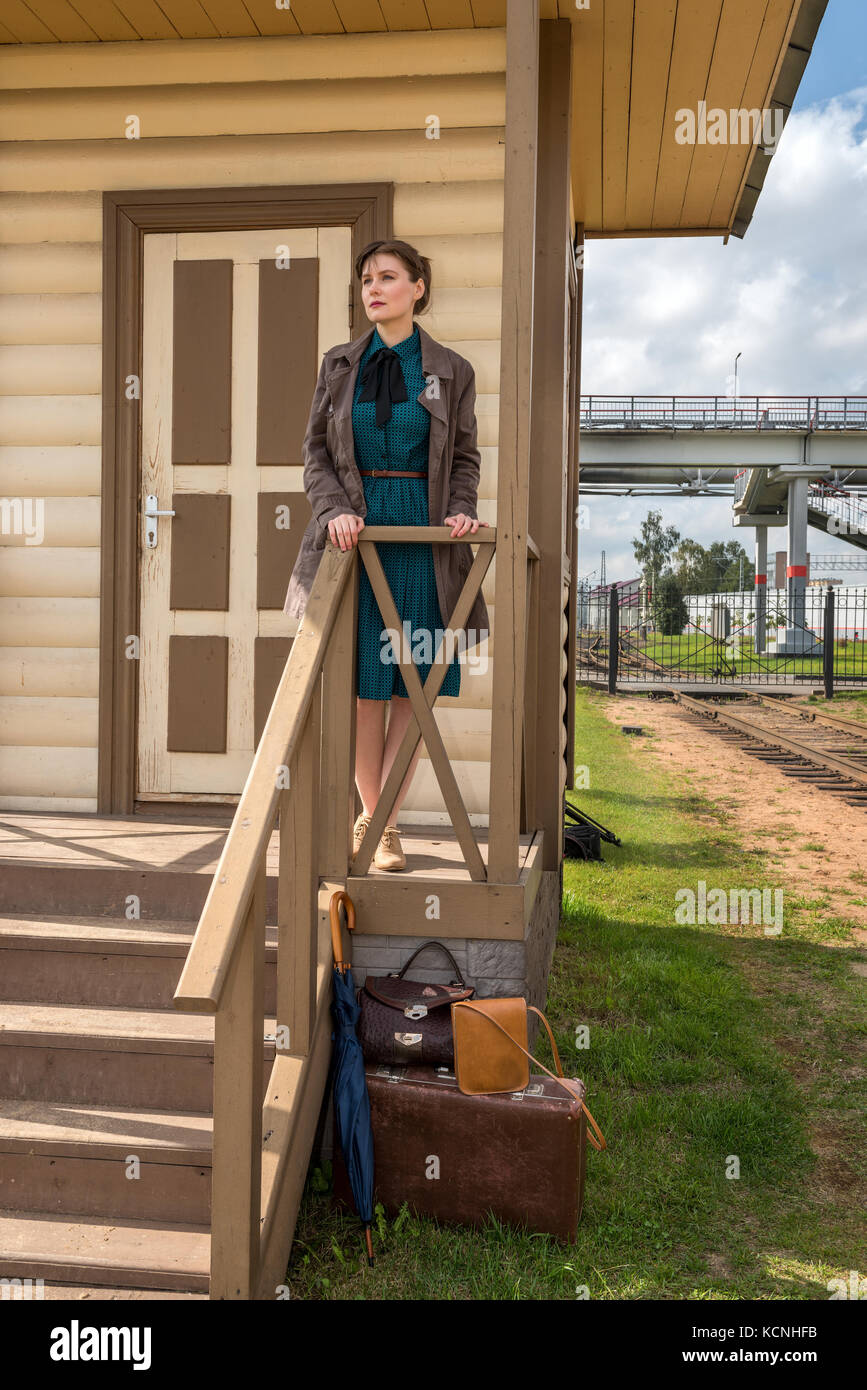 young woman waiting for the arrival of a train at a small station in retro style Stock Photo