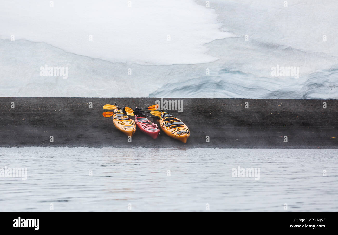 Three Kayaks lined up on the volcanic beach of Whalers Bay become the centre of interest in a simple design, Deception Island, South Shetland Islands Stock Photo