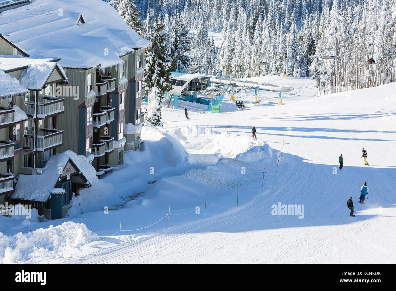 Skiers and snowboarders scoot past slopeside accommodations on Mt. Washington's Linton's Loop, The Comox Valley, Vancouver Island, Britiah Columbia, Canada Stock Photo