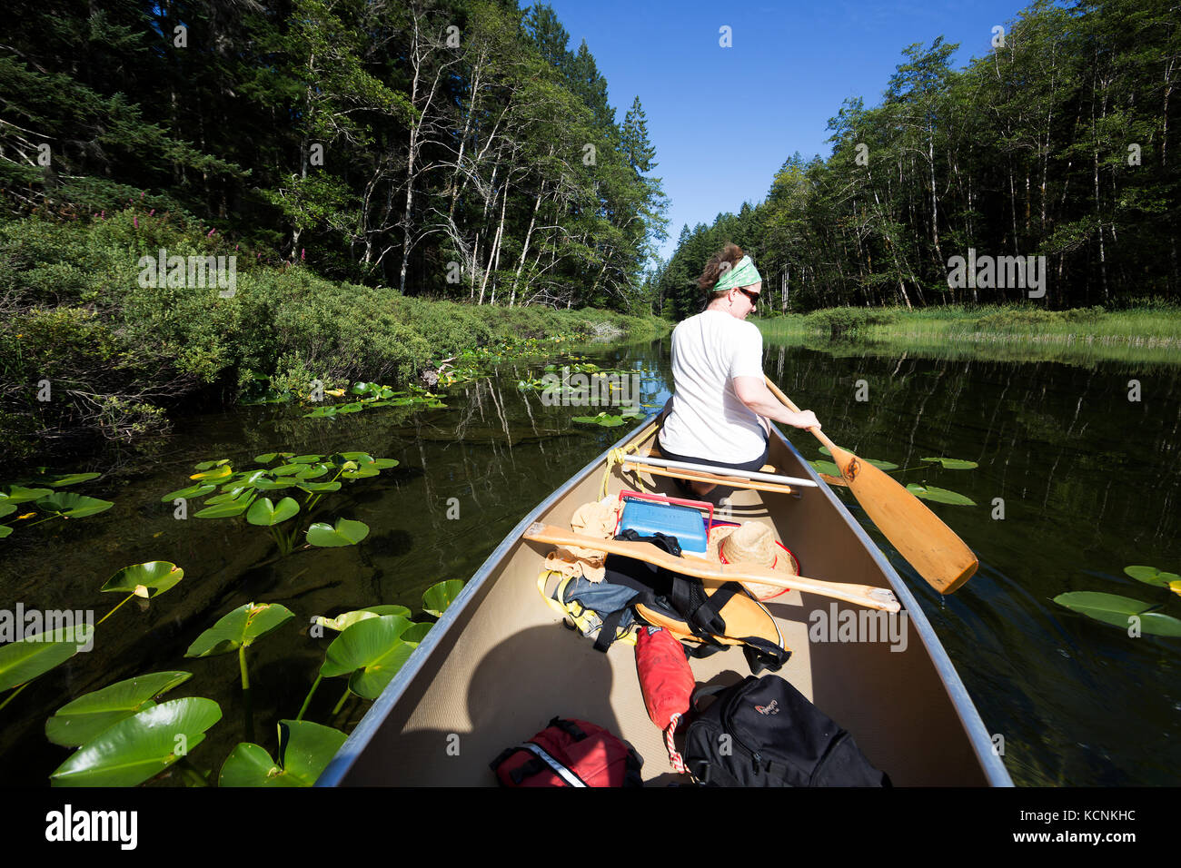 A paddler negotiates her canoe while on Village Bay Lakes on Quadra Island,  British Columbia, Canada. Stock Photo