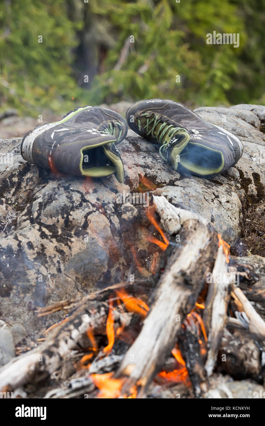 Two friends share a laugh at a camp fire while hiking on Lee Plateau.  Vancouver Island, British Columbia, Canada Stock Photo