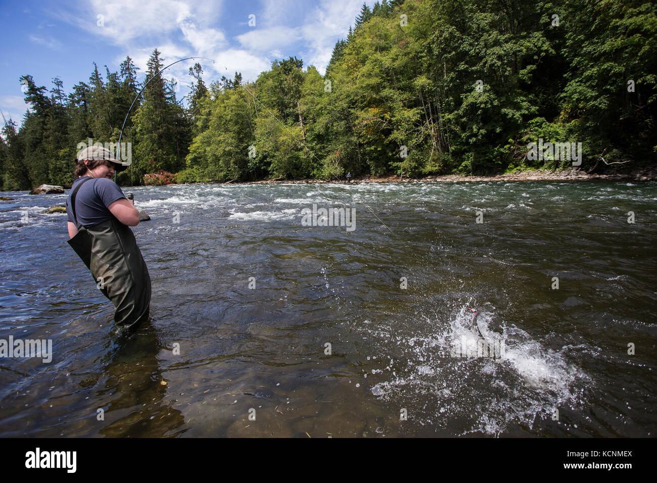 A young fisherman reels in a Salmon from the Campbell River, Vancouver Island, Canada Stock Photo