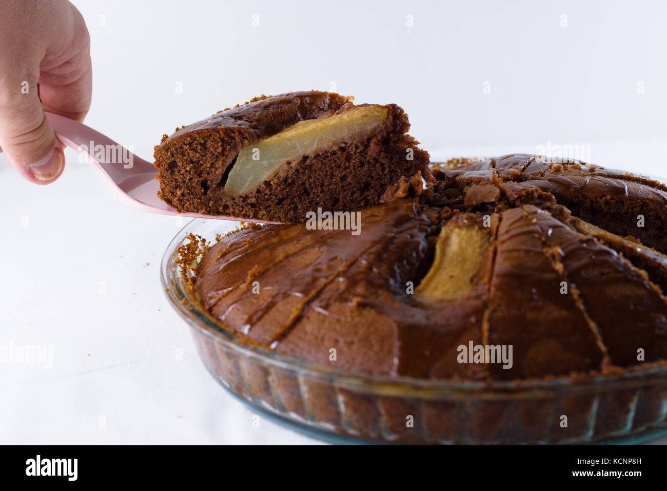 Slice of pear pie being served by caucassian hand on white background Stock Photo