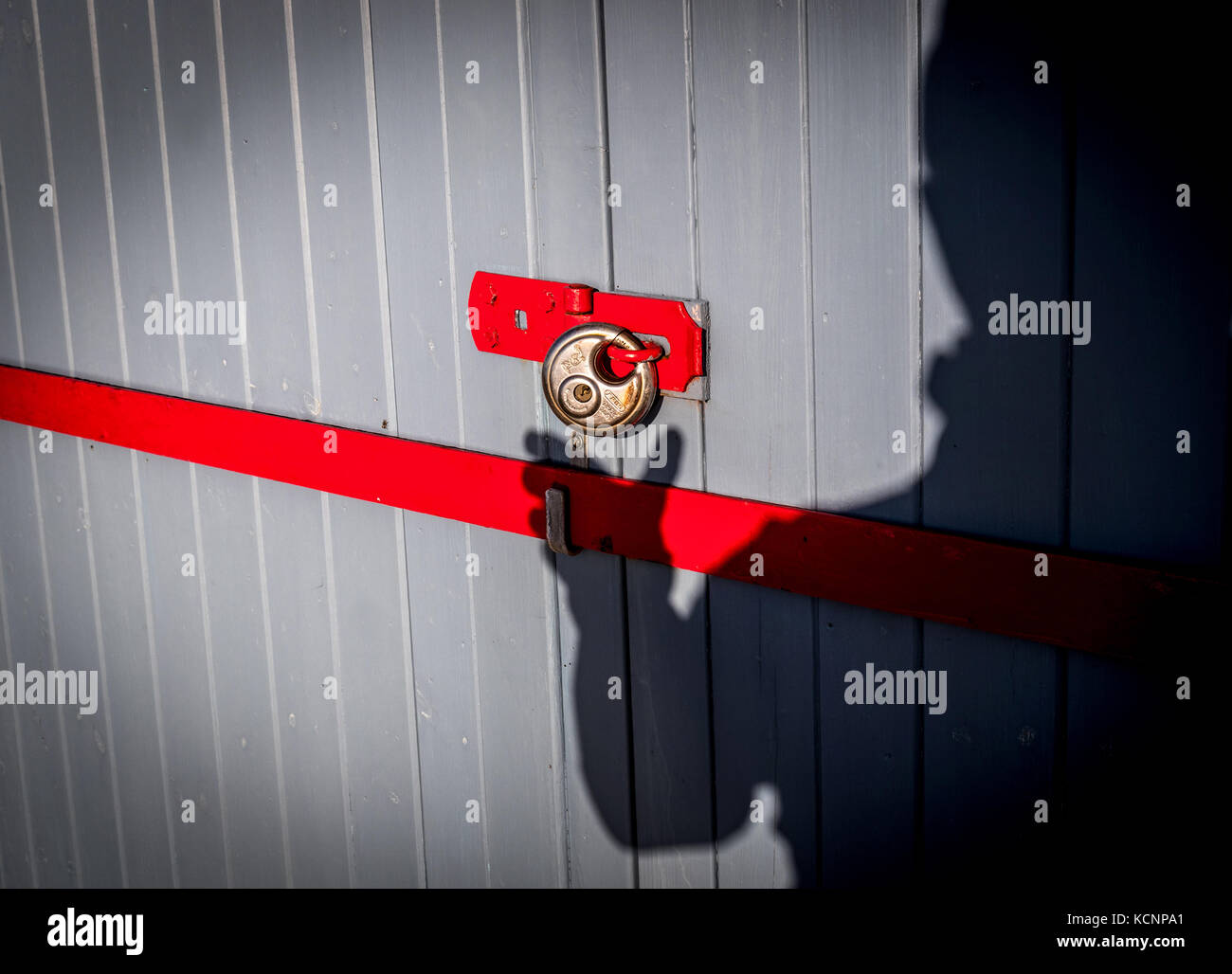 Shed theft concept image of a shadowy figure approaching a locked shed Stock Photo
