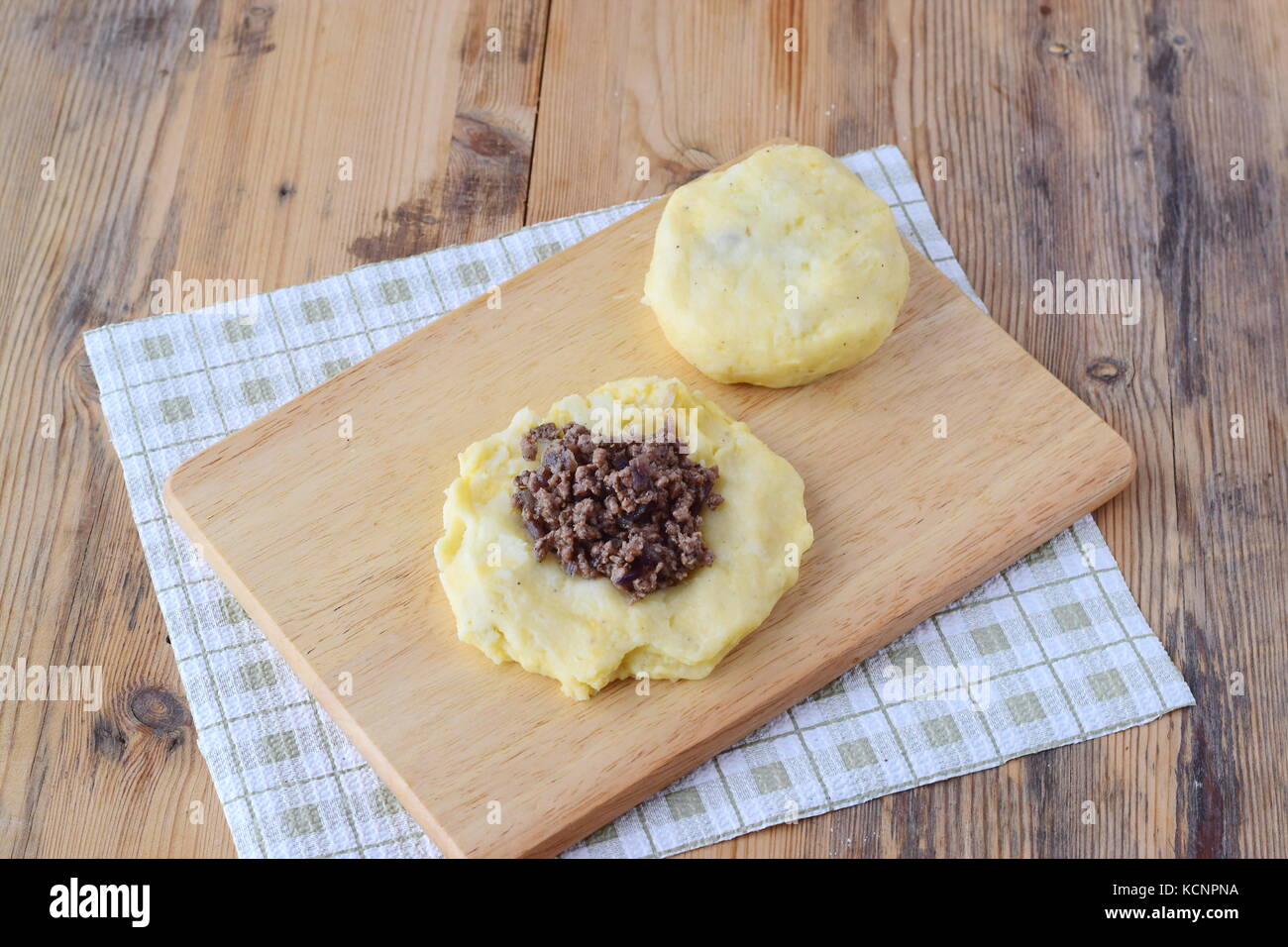Potato dumplings stuffed with minced meat on a wooden cutting board. Step by step cooking. Healthy eating concept Stock Photo