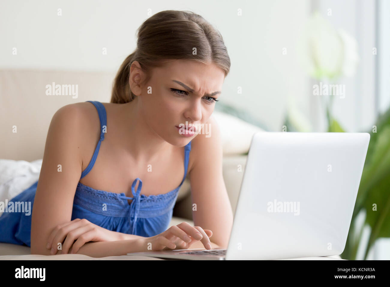 Confused young woman having problem with computer, looking at laptop screen, reading warning about virus detected or operation error, malware alert, e Stock Photo