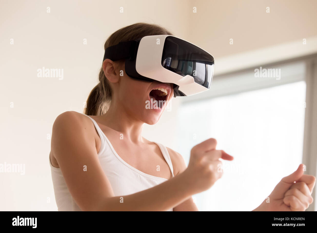 Young female gamer in wearable VR headset playing action 3d video game at  home, excited teen holding wheel and screaming driving digital racing car  in Stock Photo - Alamy