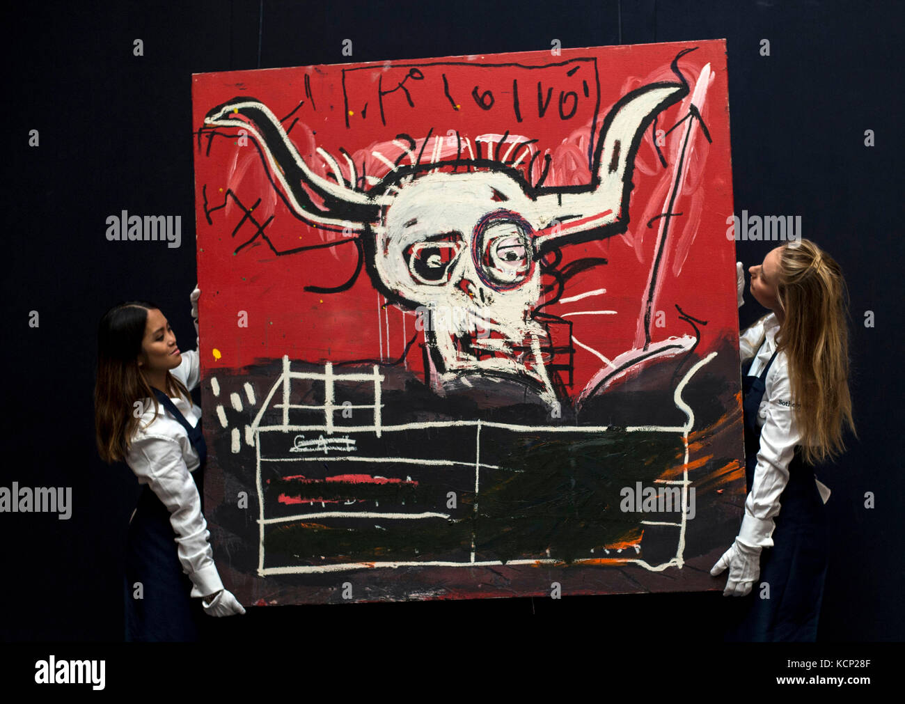Sotheby's employees hold Jean-Michel Basquiat's Cabra, 1981-1982, during a photo call for highlights from forthcoming sales of contemporary and impressionist and modern art in New York, at Sotheby's in London. Stock Photo