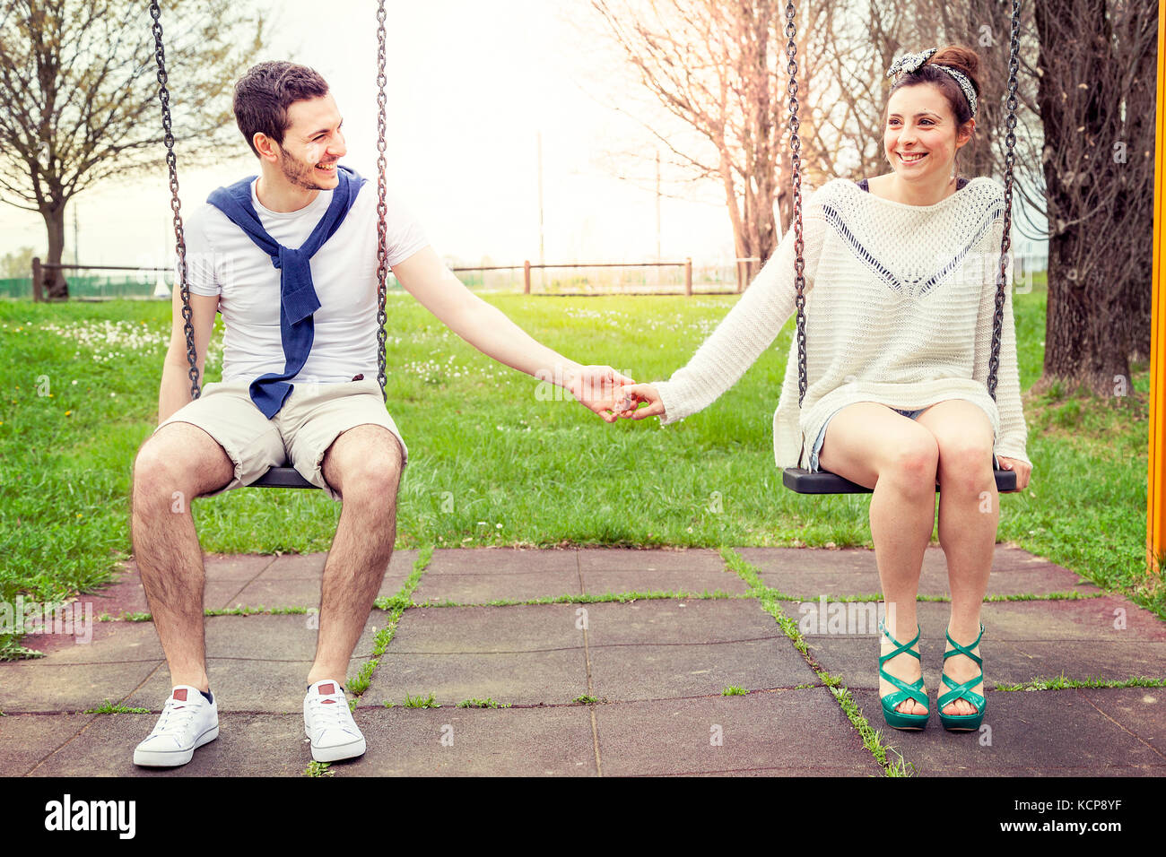 pair of young lovers hand in hand on the swing outdoor in the park Stock  Photo - Alamy