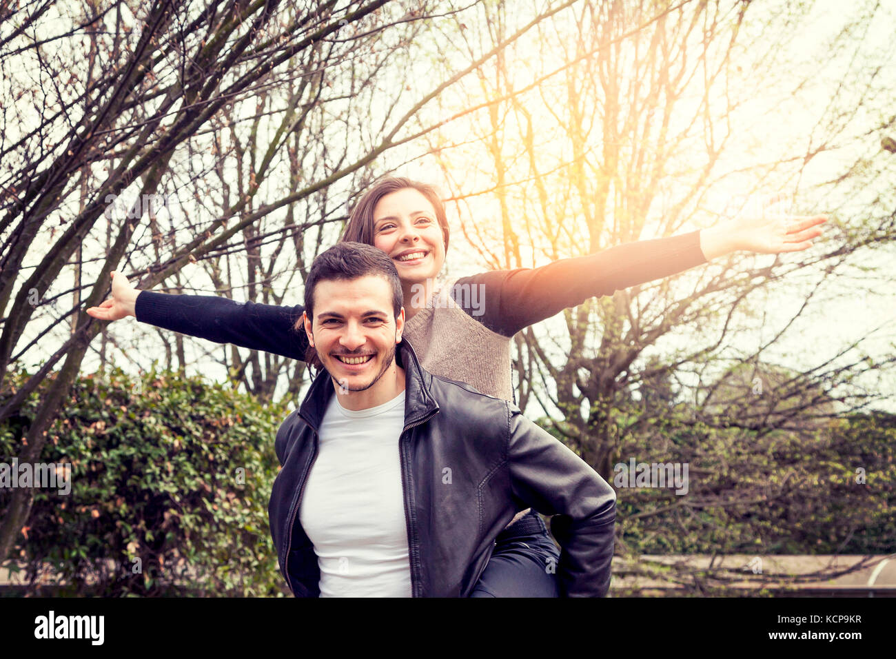 young boy have fun wearing her girlfriend on his shoulders over a wooden deck Stock Photo