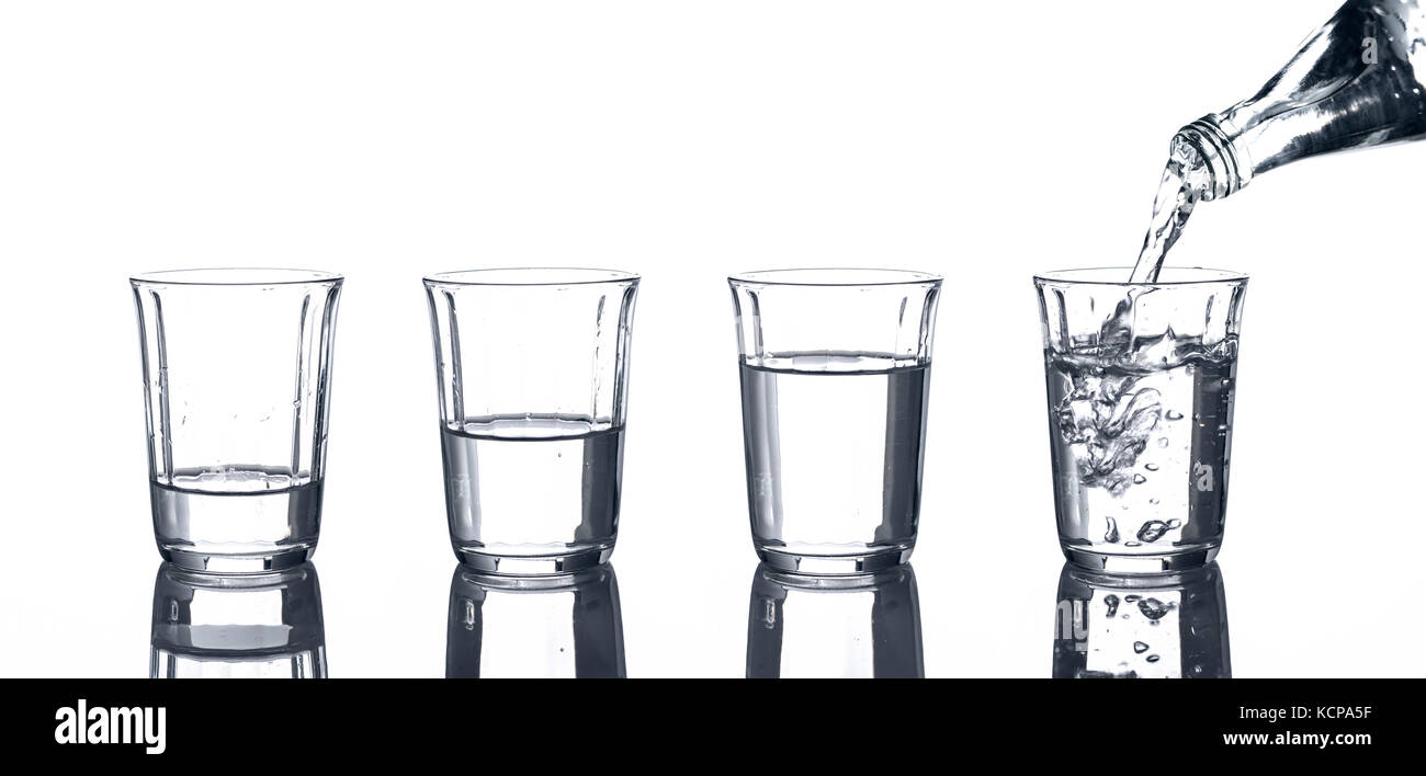 4 glasses with water and a bottle from which is poured Stock Photo - Alamy