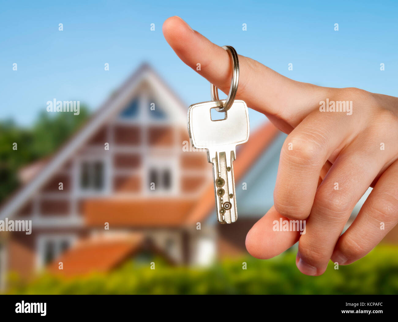 Hand holding a key in front of a country house Stock Photo