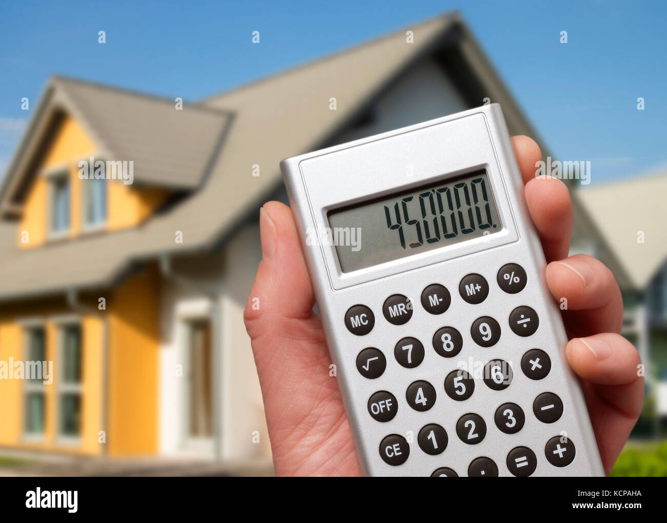 Calculator with a high sum in front of a modern family house Stock Photo