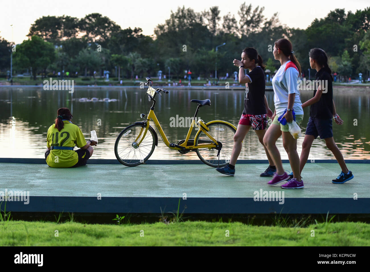Phuket, Thailand. 5th Oct, 2017. People walk past an ofo sharing-bike at a public park in Phuket, Thailand, Oct. 5, 2017. China's dock-less bike-sharing company ofo provided more than 1,000 bikes in Phuket's key locations in late September and offered a 1-month free trial without deposit fee. Now the bike-sharing service has benefited local residents and tourists. Ofo's regular service fee will be charged at 5 Baht per 30 minutes usage, with a deposit fee of 99 Baht. Credit: Li Mangmang/Xinhua/Alamy Live News Stock Photo