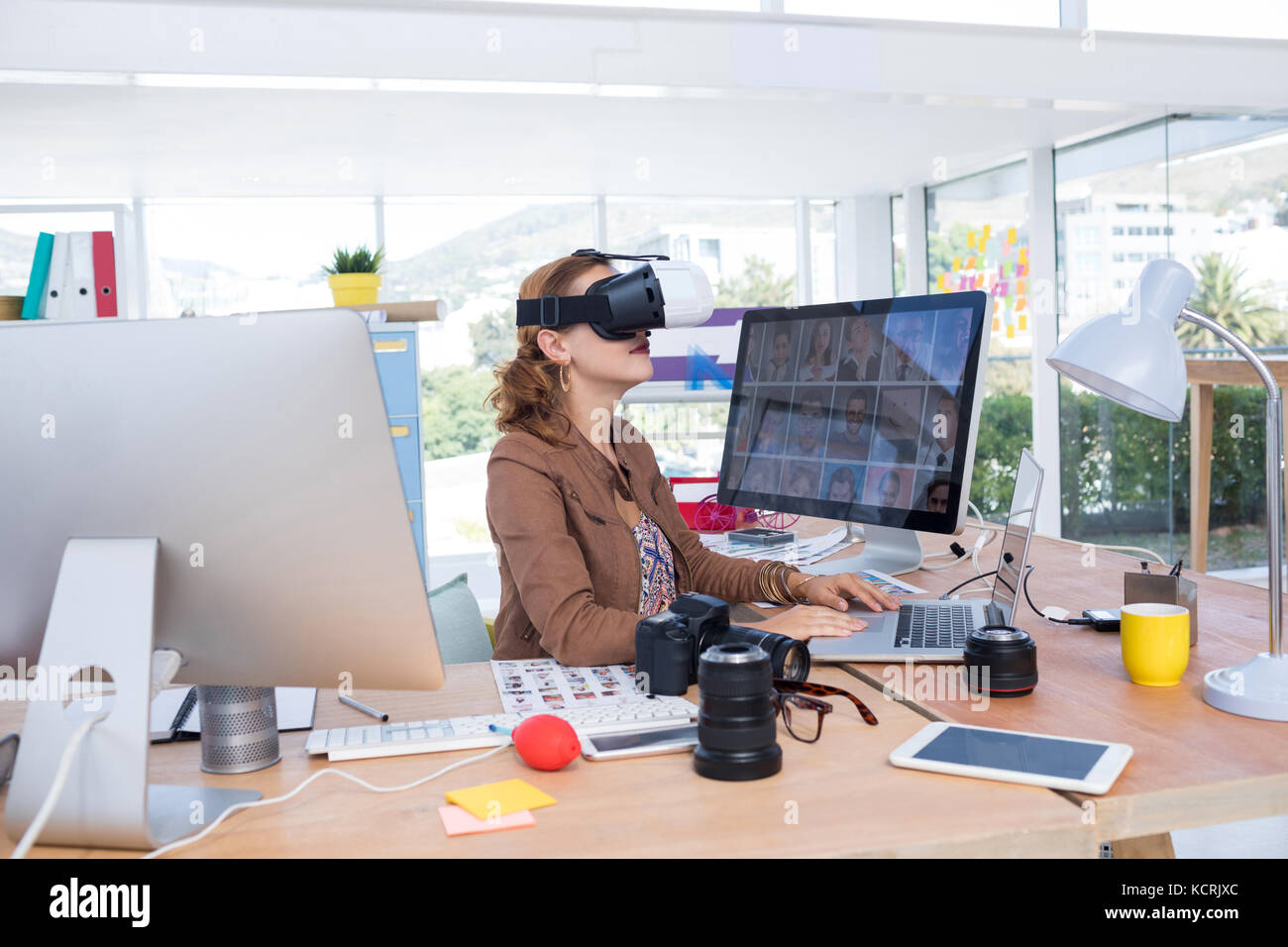 Female executive working on laptop while using virtual reality headset ...