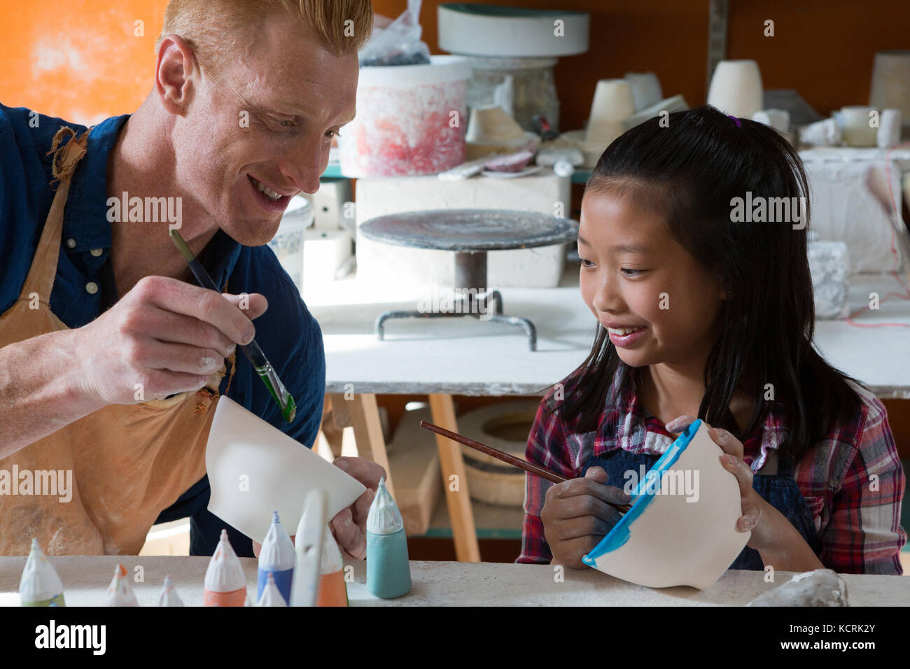Male potter and girl painting bowl in pottery workshop Stock Photo - Alamy