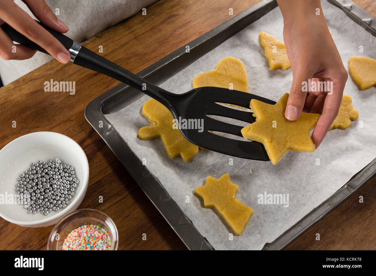 Mid-section of man placing gingerbread cookies in baking tray Stock Photo