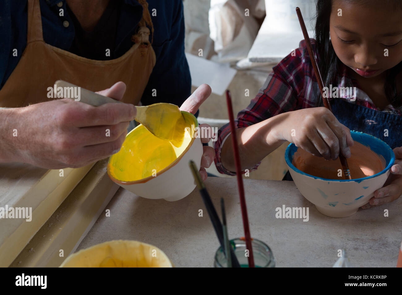 Male potter and girl painting bowl in pottery workshop Stock Photo - Alamy