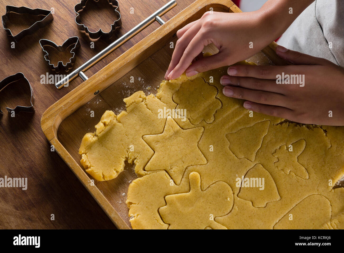 Mid-section of man removing gingerbread dough on wooden table Stock Photo