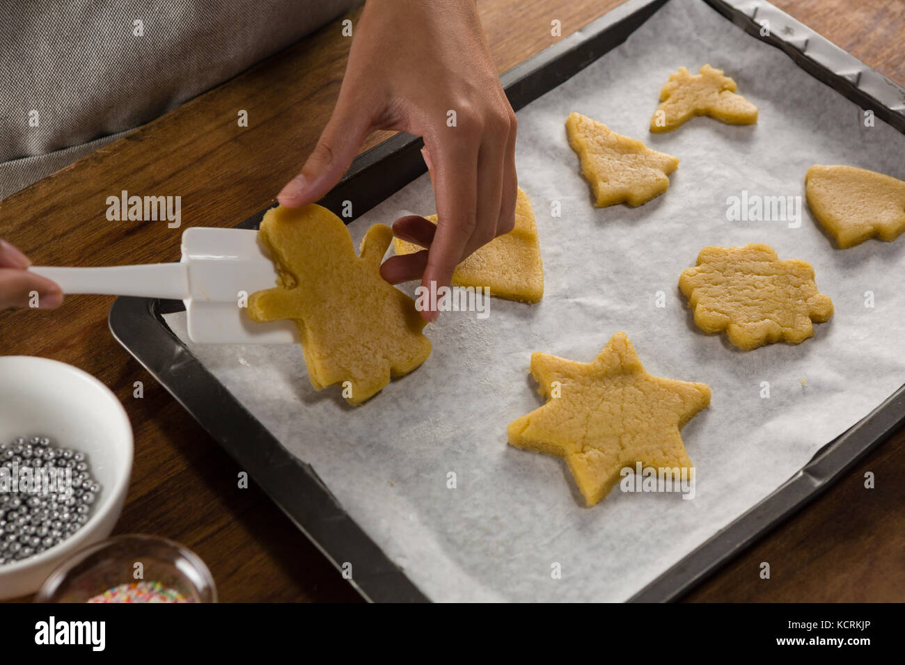 Mid-section of man placing gingerbread cookies in baking tray Stock Photo