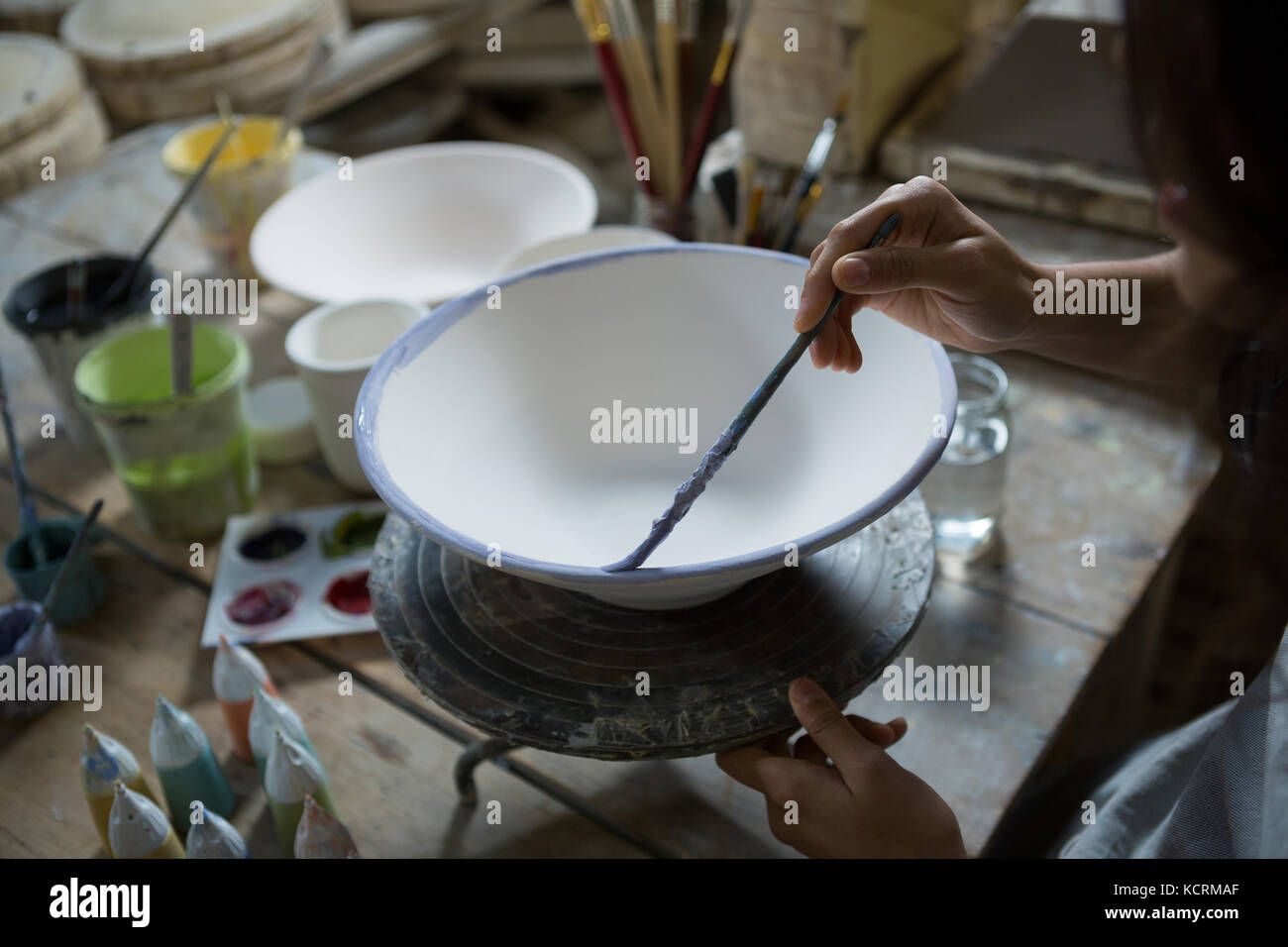 Female potter painting bowl in pottery workshop Stock Photo - Alamy