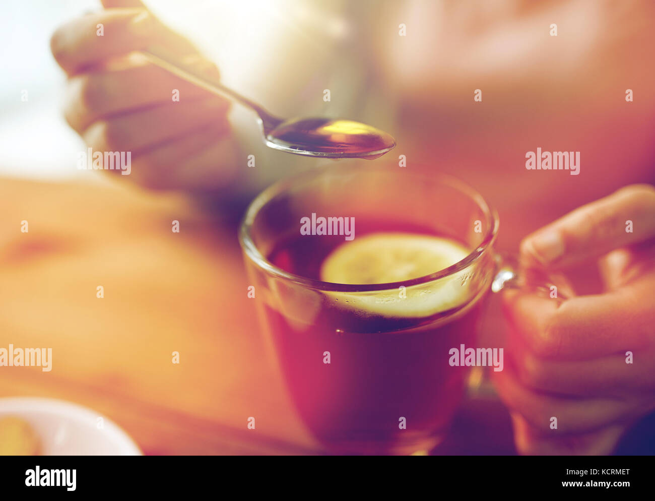 Close up of woman adding honey to tea with lemon stock photo alamy