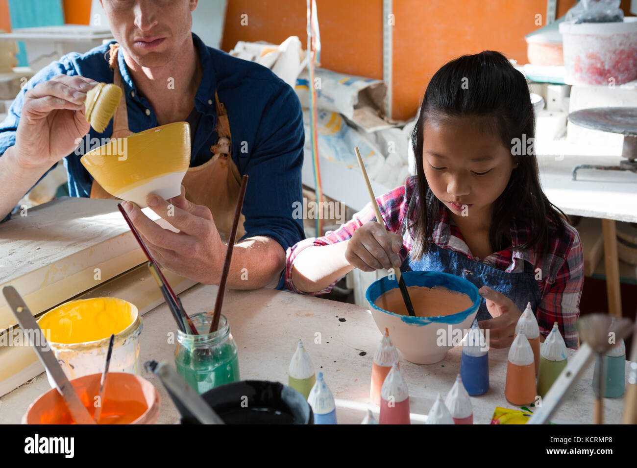Male potter and girl painting bowl in pottery workshop Stock Photo - Alamy