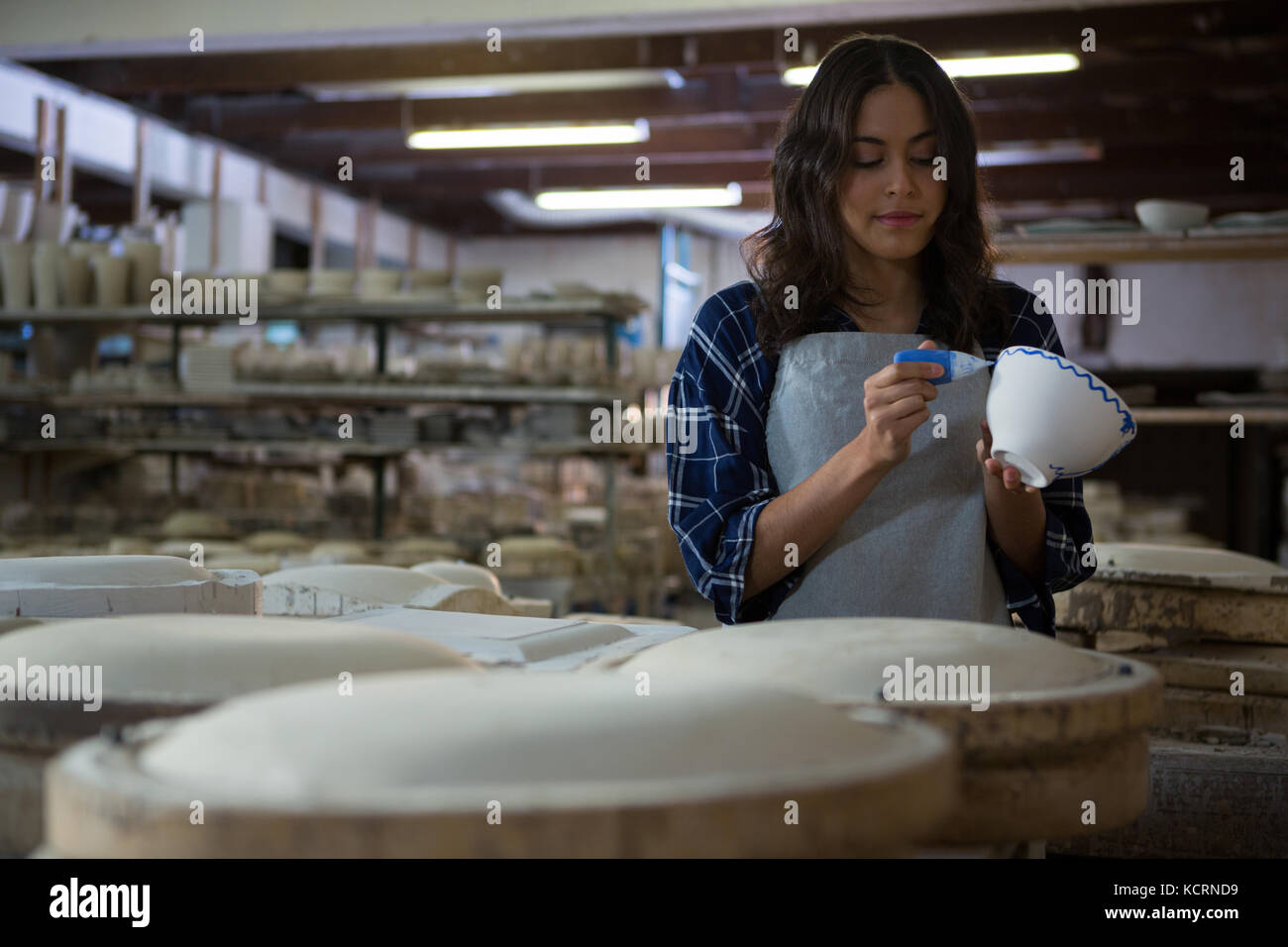 Female potter painting a bowl in pottery workshop Stock Photo - Alamy