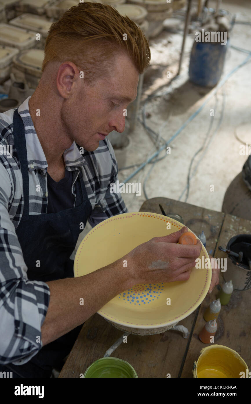 Attentive male potters painting a bowl in pottery Stock Photo