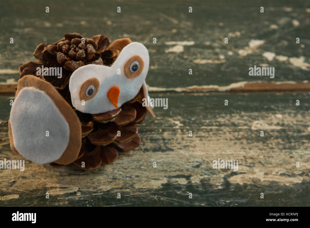Close up of owl decoration made with pine cone on wooden table Stock Photo
