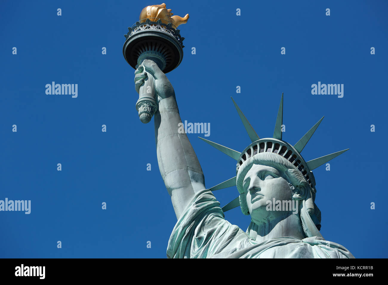 Statue of Liberty with golden torch in a sunny day, blue sky in New York Stock Photo