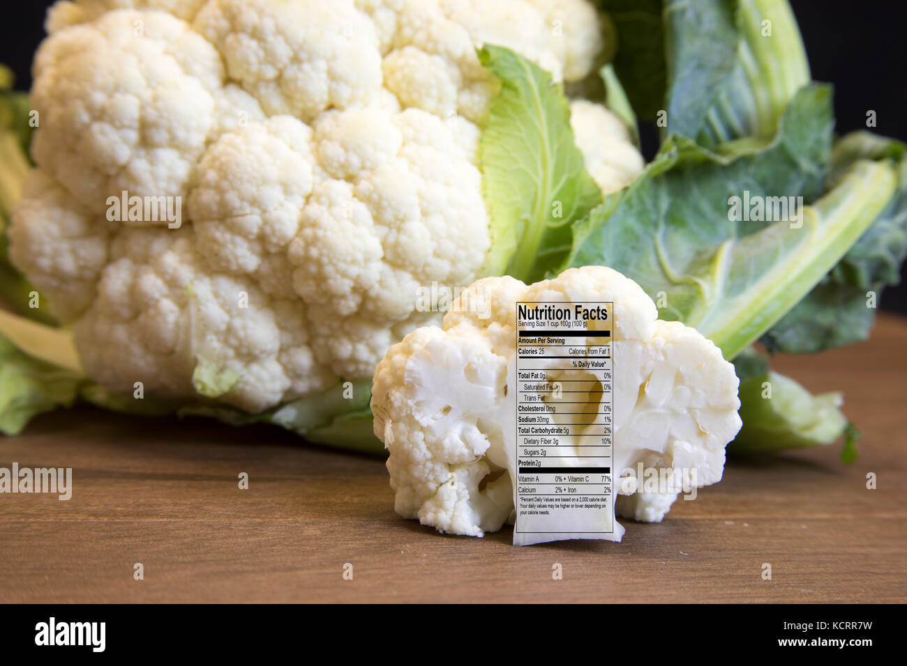 Close up of freah raw cauliflower head and floret with nutritional facts label on wooden board. Stock Photo