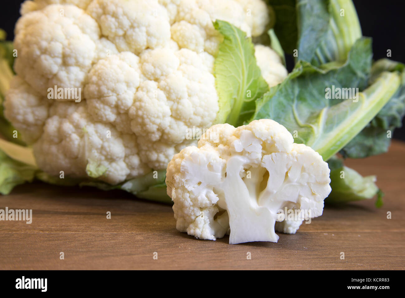 Close up of freah raw cauliflower head and floret on wooden board. Stock Photo