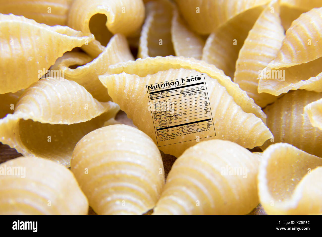 Close up of dry uncooked whole wheat small shell pasta noodle with nutrition label. Stock Photo