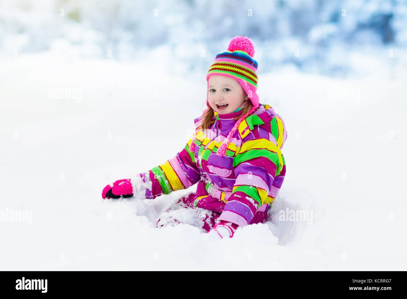Child playing with snow in winter. Little girl in colorful jacket and ...