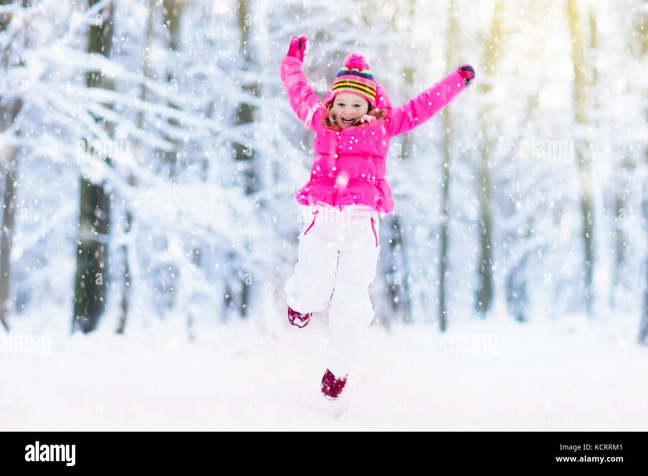 Child playing with snow in winter. Little girl in colorful jacket and ...