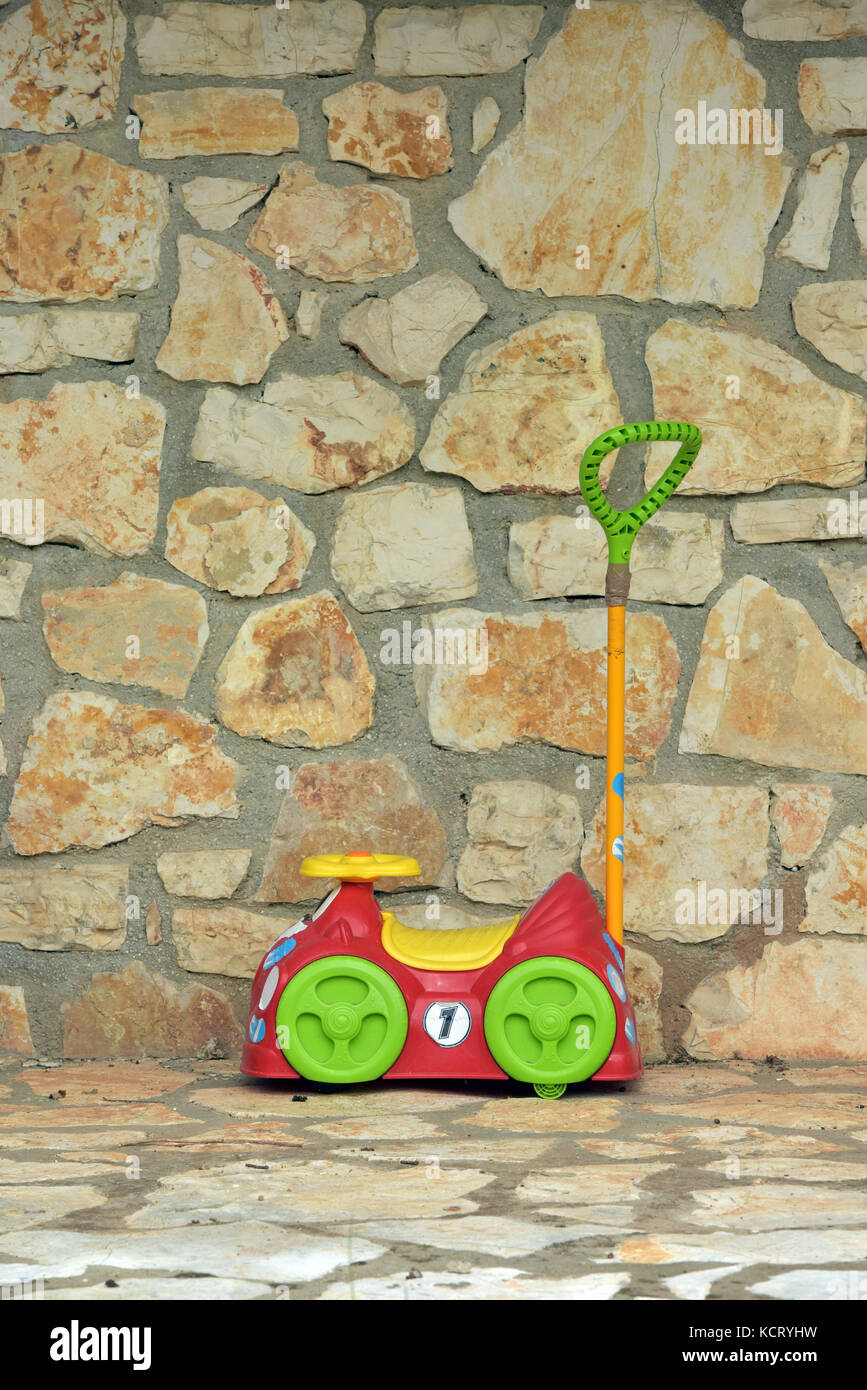 a small childrens ride on or push along toy with a handle for pushing