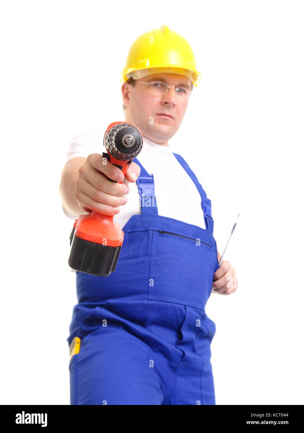 Construction worker wearing blue overall and yellow helmet pointing with  drilling machine over white background Stock Photo - Alamy