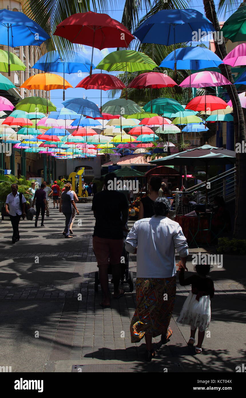 Port Louis, Mauritius - tourists and shoppers walk in an umbrella covered lane in the Le Caudan Waterfront in the capital Stock Photo