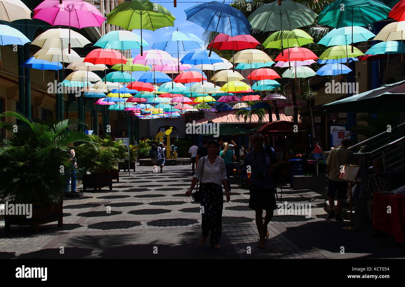 Port Louis, Mauritius - tourists and shoppers walk in an umbrella covered lane in the Le Caudan Waterfront in the capital Stock Photo