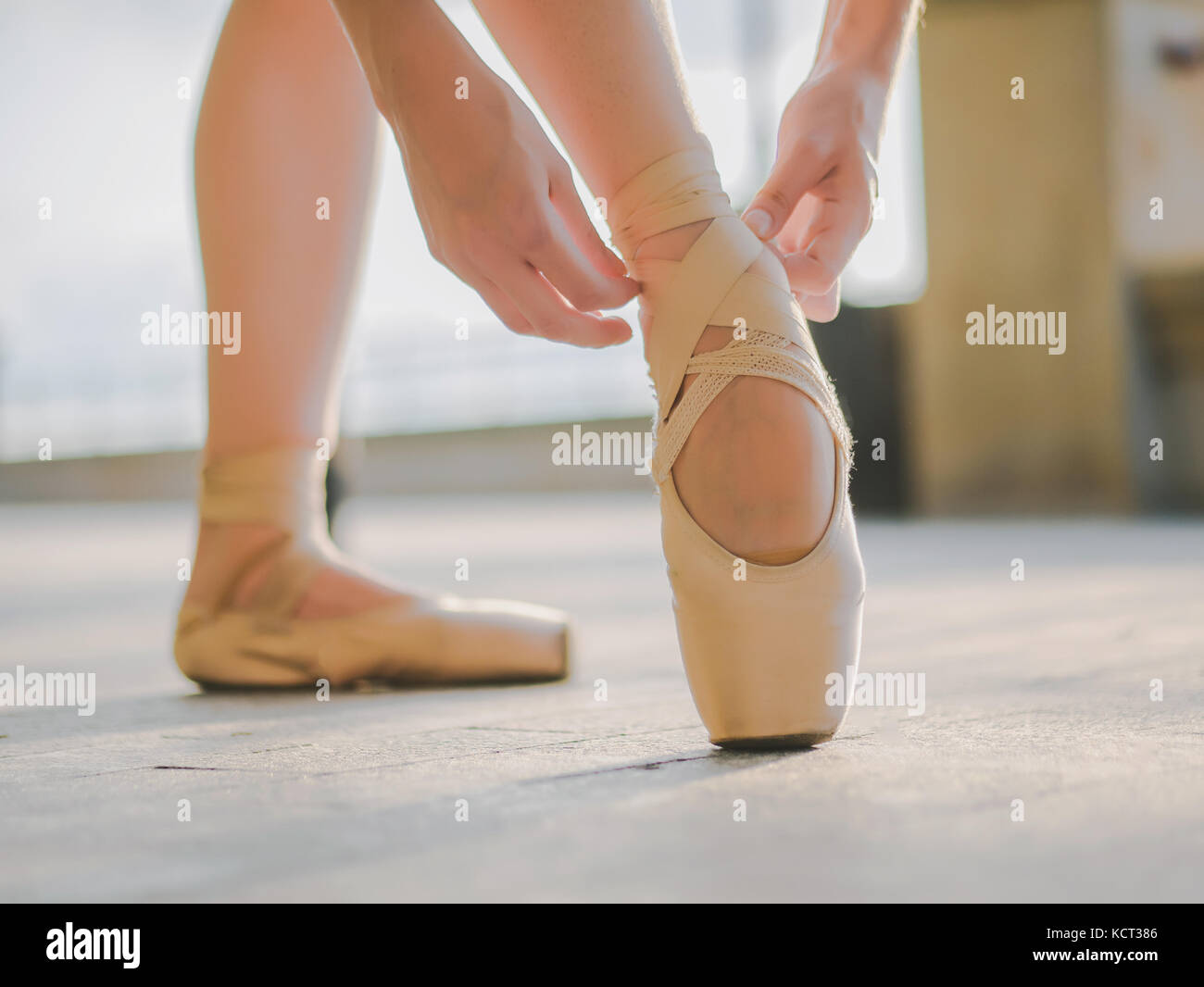 Close up of a ballet dancer's feet as she practices pointe exercises on the stone embankment. Woman's feet in pointe shoes. Ballerina shows classic ba Stock Photo