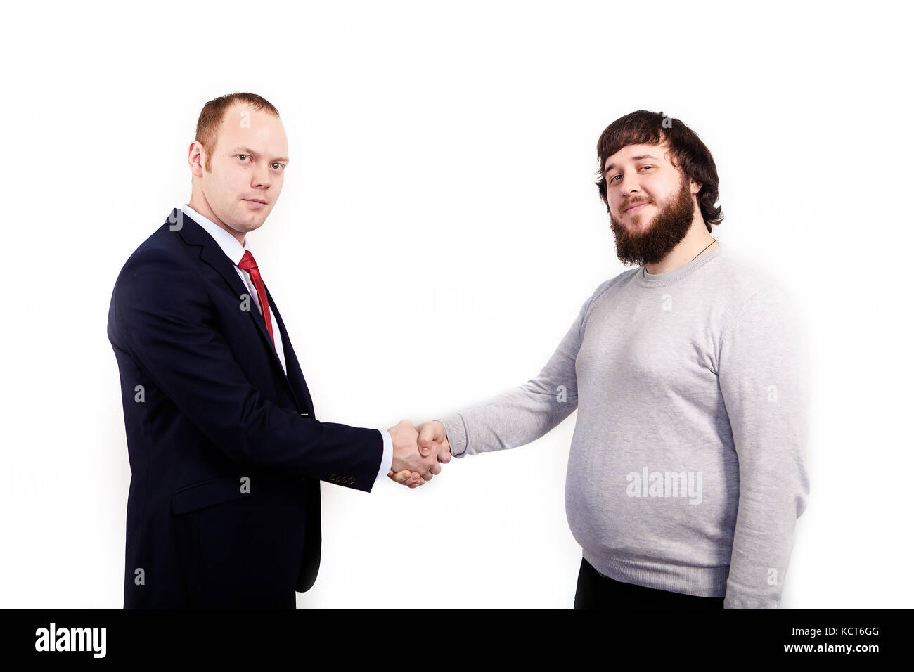 Sealing a deal Two happy young men shaking hands while sitting in the rest area of the office. Stock Photo